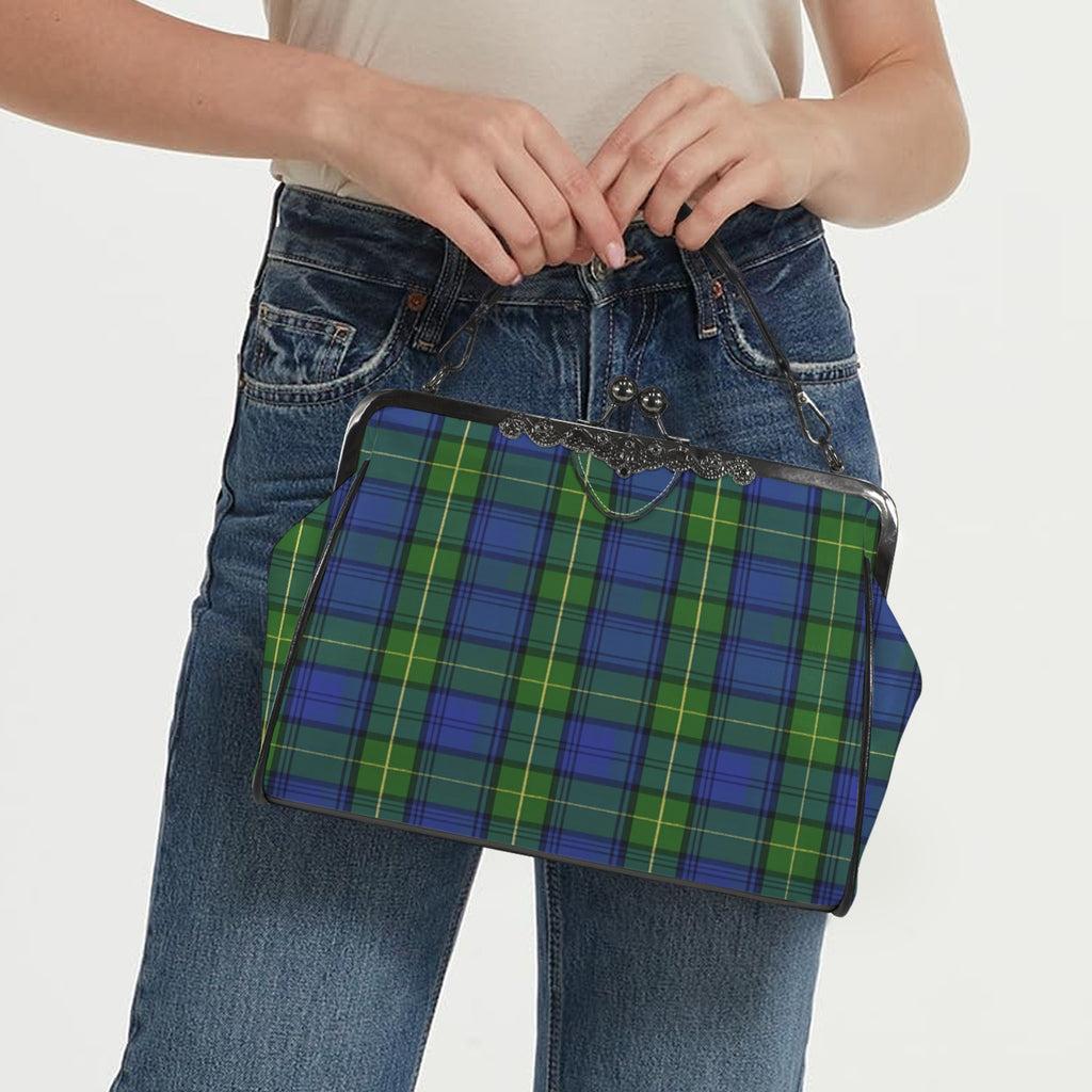Model carrying kisslock bag with blue and green plaid pattern by the top handle