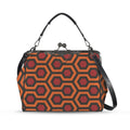 Kisslock crossbody bag with burnt-orange and red Haunted Hotel geometric print, front view with handle and shoulder strap