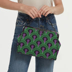 Model carrying kisslock bag with green arches and purple keyhole pattern by the top handle