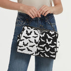 Model carrying kisslock bag with black and white bat pattern by the top handle