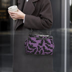 Model wearing kisslock bag with purple and black bat pattern at her side