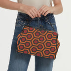 Model carrying kisslock bag with burnt-orange and red Haunted Hotel geometric print by the top handle