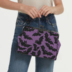 Model carrying kisslock bag with purple and black bat pattern by the top handle