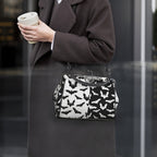 Model wearing kisslock bag with black and white bat pattern at her side